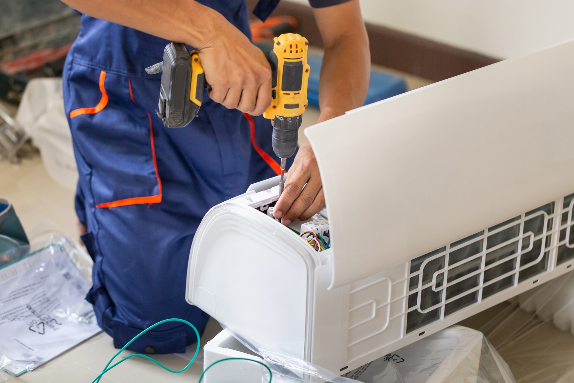 Asian technician man installing an air conditioning in a client house, Young repairman fixing air conditioner unit, Maintenance and repairing concepts